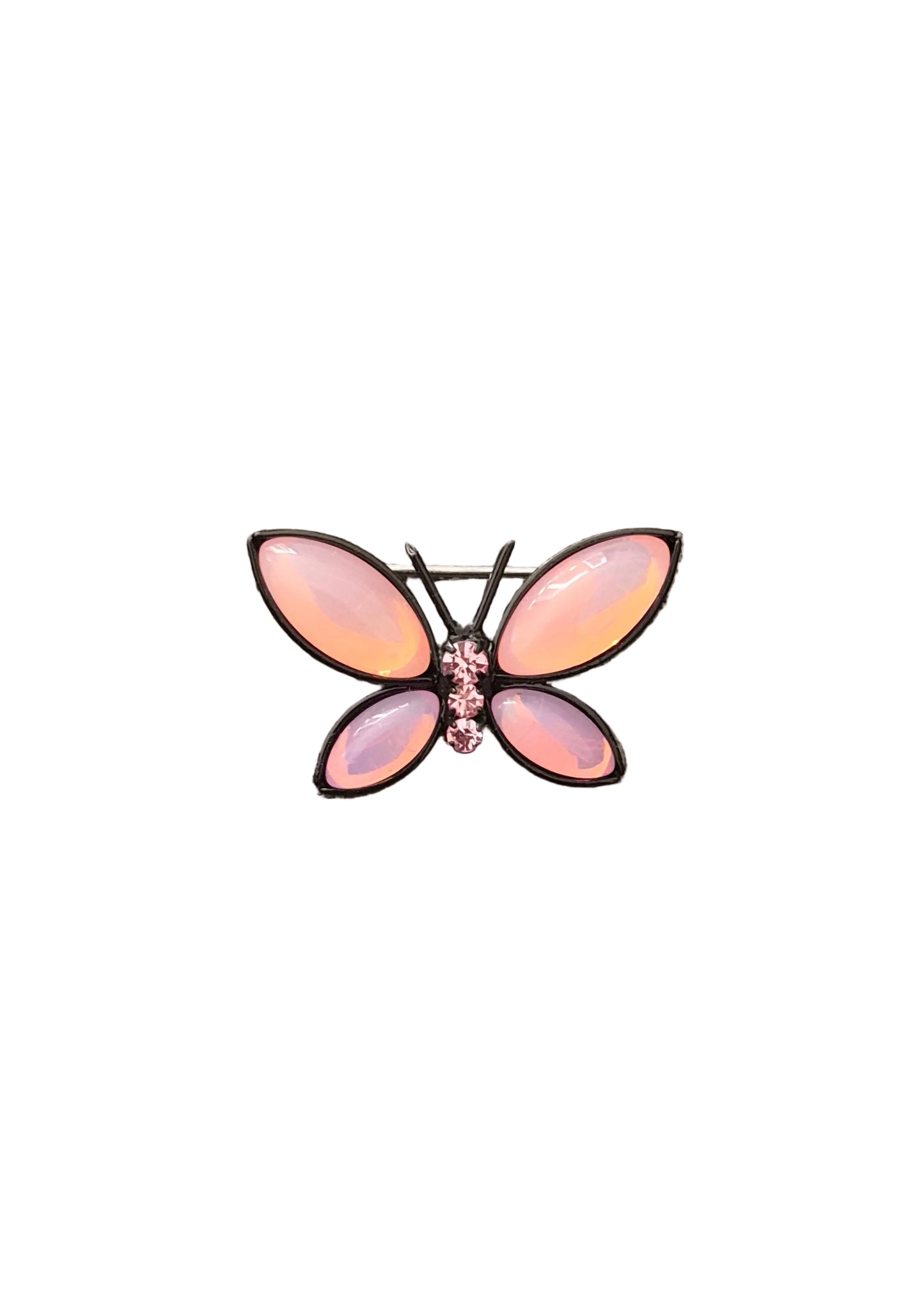 A butterfly-shaped brooch with iridescent pink and peach wings and a small pink rhinestone center, set in a dark metal frame.