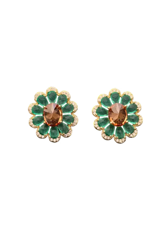 A pair of vintage-style flower-shaped earrings with green enamel petals, gold-toned metal borders, and a central oval brown gemstone,.