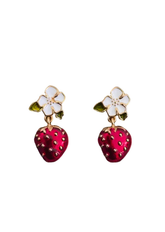 A pair of strawberry and flower drop earrings. Each earring features a gold-tone metal setting with a white enamel flower and a dangling red enamel strawberry with small gold seed details.