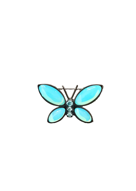 A butterfly-shaped brooch with light blue opal-like wings and a small cluster of clear rhinestones at the center, set in silver-toned metal.