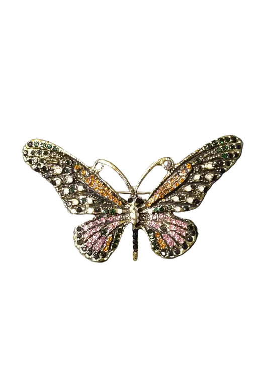 A butterfly-shaped brooch with intricate gold-toned metalwork, pink rhinestones on the lower wings, and green rhinestones on the upper wings